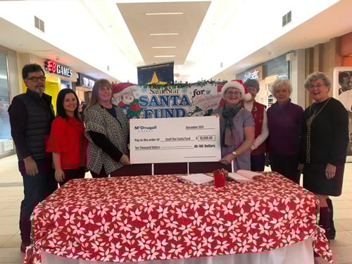 Christmas Cheer Receives $10,000 from McDougall Energy to Help Those in Need 152 Shows 7 people standing in a shopping mall holding a large cheque from McDougall Energy during Christmas