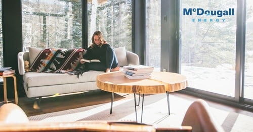 Preparing your home for colder weather 122 Shows a woman reading a book sitting on a large couch in a large room surrounded by windows