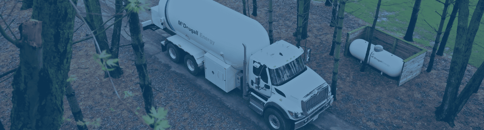 Clean energy fuel delivery truck in a forested area by McDougall Energy.
