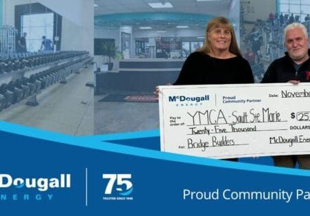 McDougall Energy team member poses with the YMCA staff with presentation cheque