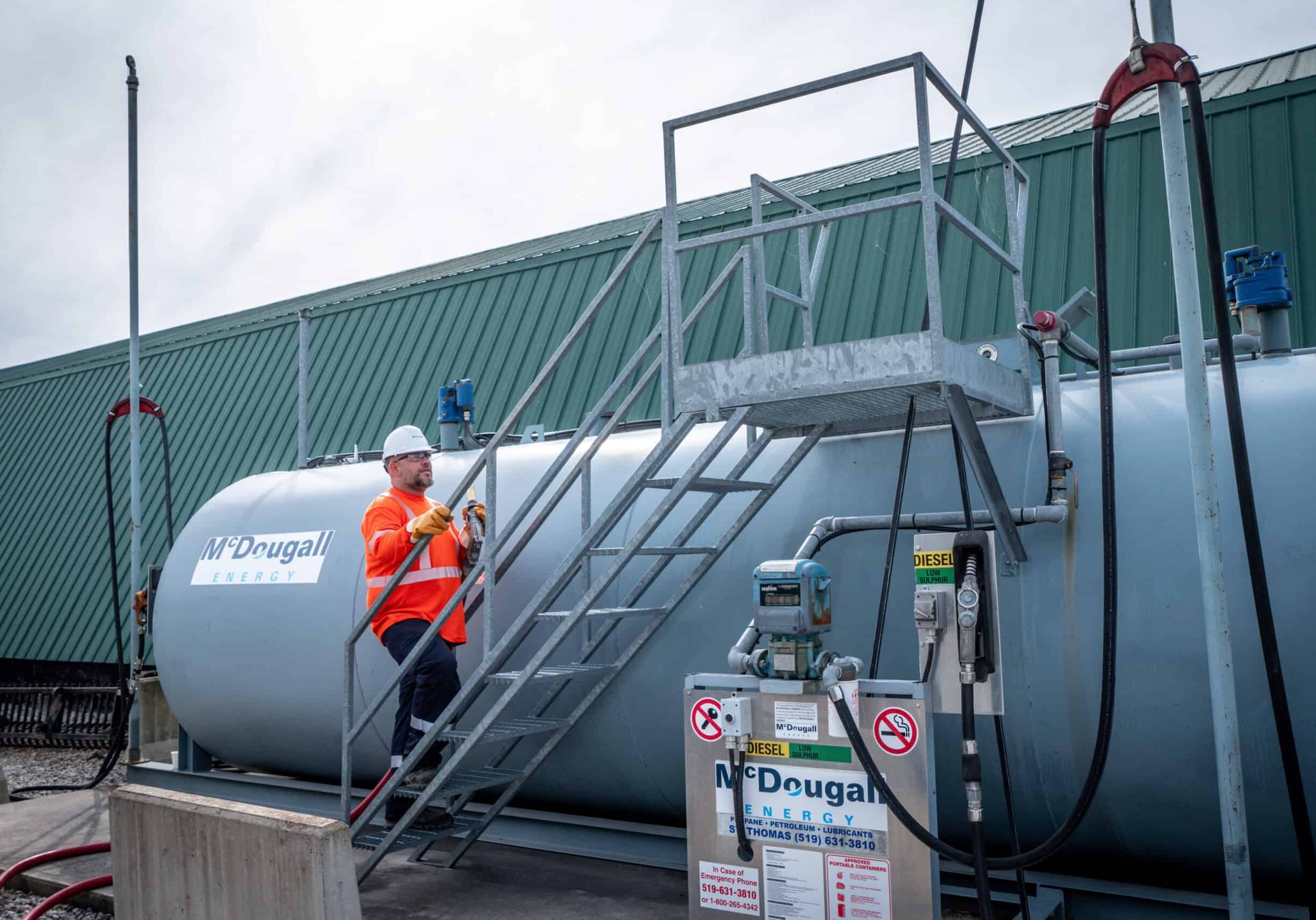 Propane storage tank at McDougall Energy fueling station with technician inspecting safety controls.