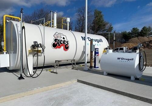 Shows outdoor shot of large white tank with Mcdougall Energy logo on it and Aces logo