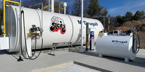 Shows outdoor shot of large white tank with Mcdougall Energy logo on it and Aces logo