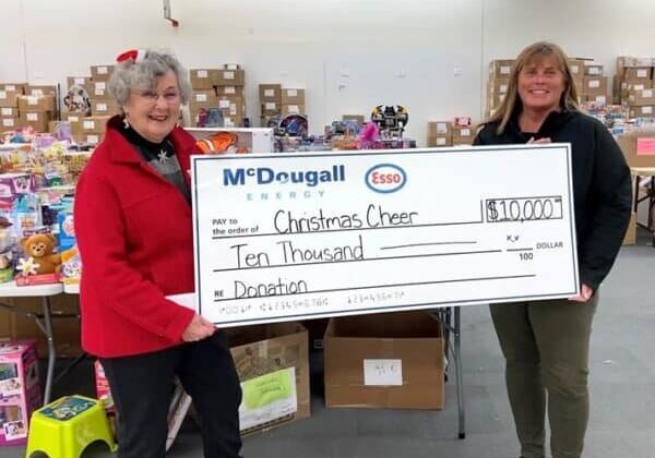 $10,000 donation check for Christmas Cheer by McDougall Energy at charity event.