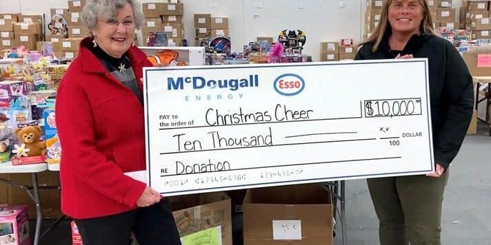 $10,000 donation check for Christmas Cheer by McDougall Energy at charity event.