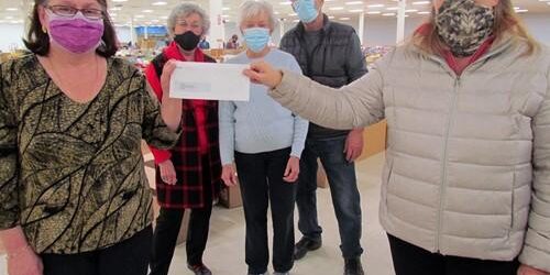 Shows 2 people in a store holding a cheque from McDougall Energy and 3 people behind them
