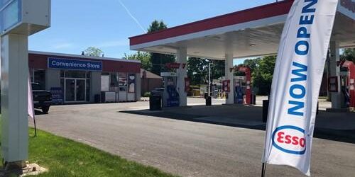 Shows exterior shot of Esso gas station with a large stake banner with words Esso Now Open