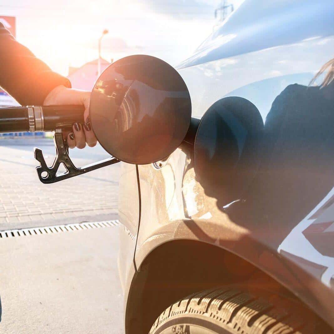 Gasoline fueling a car at a station during sunset.