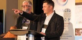 Shows man at a podium pointing into the crowd