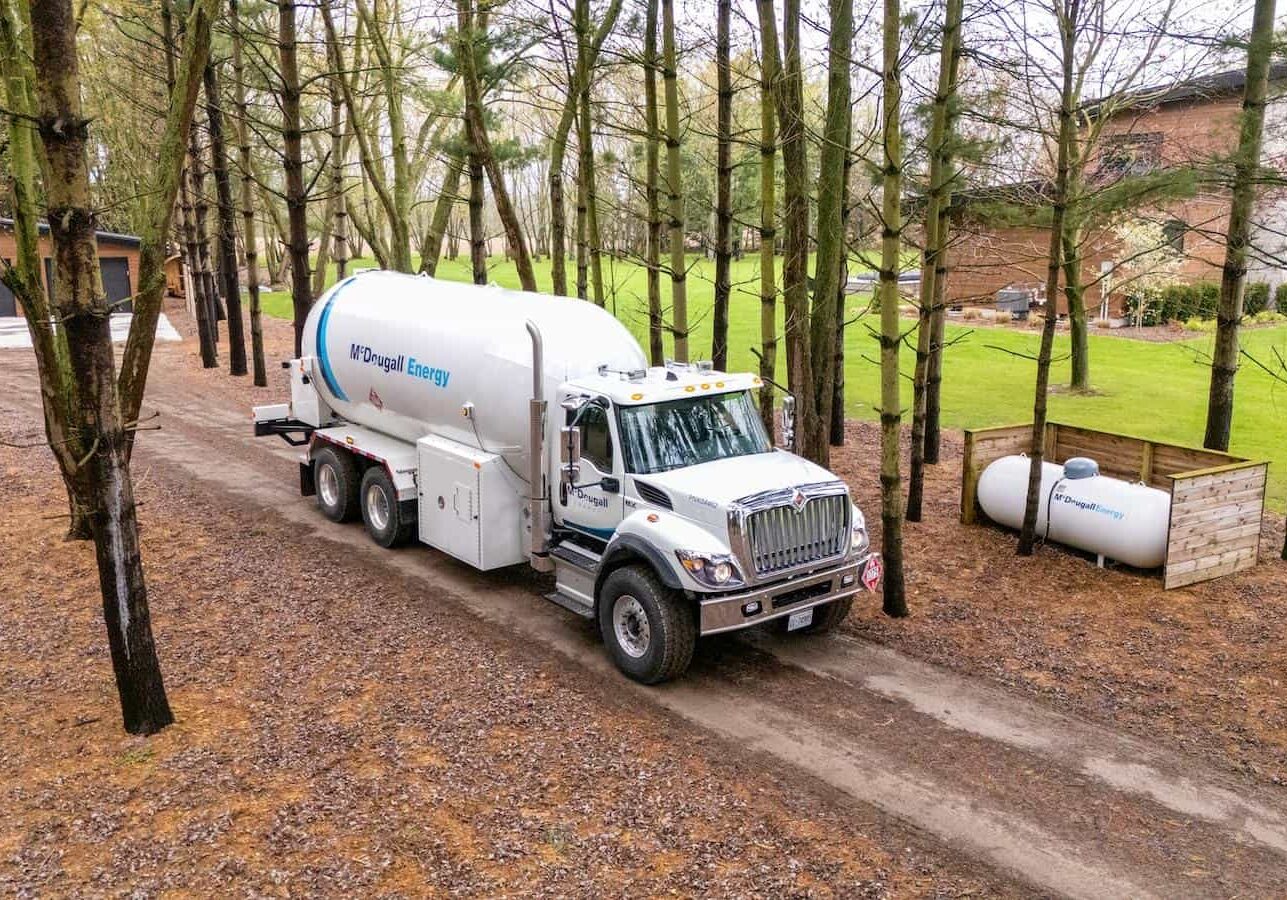 McDougall truck on dirt road in rural area in surrounded by trees and fall leaves