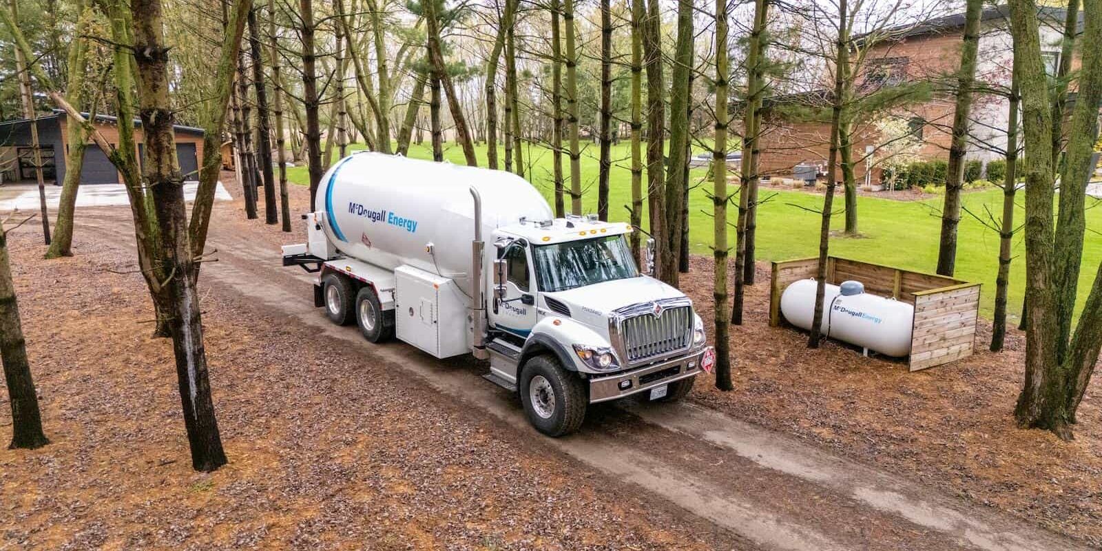 McDougall truck on dirt road in rural area in surrounded by trees and fall leaves