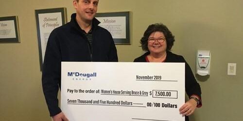 Shows 2 people holding a large cheque from McDougall Energy