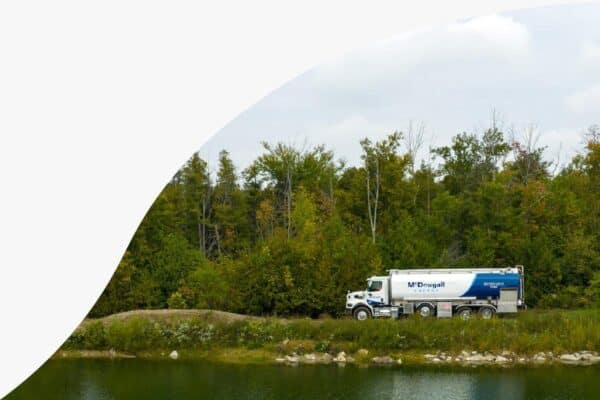 Fuel delivery truck in a natural landscape with trees and water, representing McDougall Energy services.
