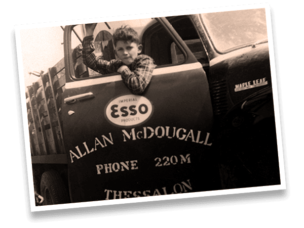 Vintage delivery truck with child leaning out window, advertising McDougall Energy services and contact info.
