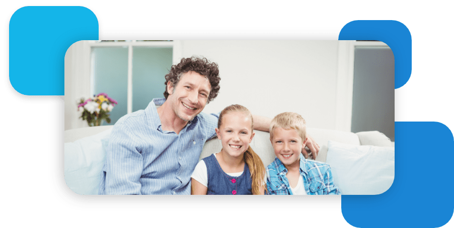 father sitting with kids on a couch smiling at camera
